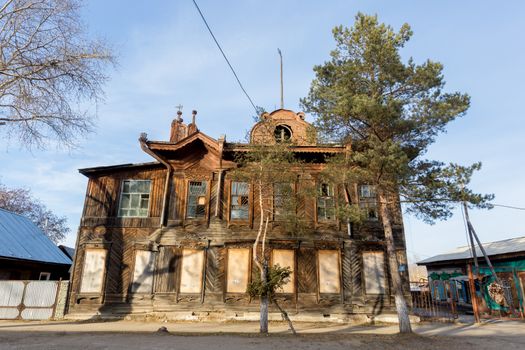 Old wooden residential two-storey house in the middle of a city street in Russia.