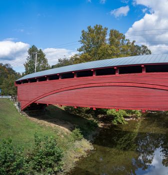 Well maintained Burr Truss covered bridge in Barrackville West Virginia crossing stream in the fall