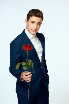 A man in a suit with a rose in his hands a gift date light background. High quality photo