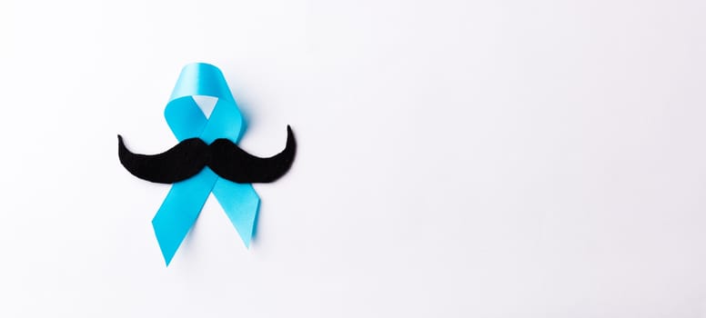 Black mustache paper and light blue ribbon, studio shot isolated on white background, Prostate cancer awareness month, Fathers day, minimal November moustache concept