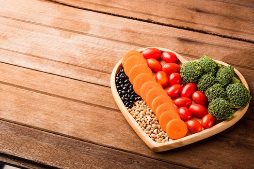 Top view of fresh organic fruits and vegetables in heart plate wood (carrot, Broccoli, tomato) on wooden table, Healthy lifestyle diet food concept