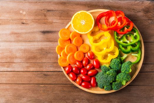 Top view of fresh organic fruits and vegetables in plate wood (carrot, Broccoli, tomato, orange, Bell pepper) on wooden table, Healthy lifestyle diet food concept