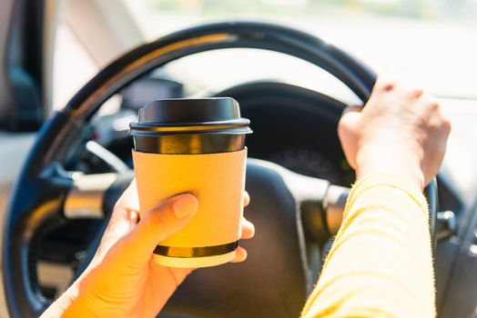 Asian woman drinking hot coffee takeaway cup inside a car and while driving the car in the morning during going to work on highway, Transportation and vehicle concept