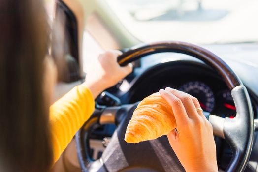 Asian woman eating food fastfood while driving the car in the morning during going to work on highway road, Transportation and vehicle concept