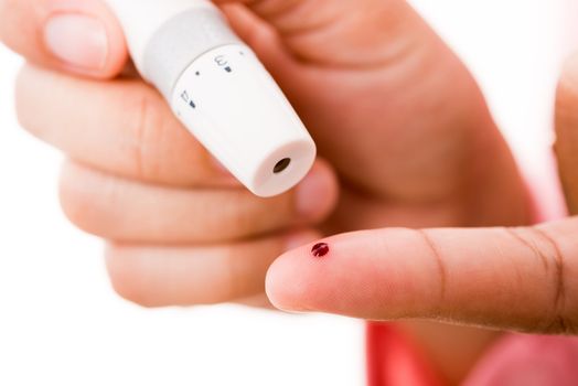 Closeup woman measuring glucose level using a hand test lancelet on the finger she monitors high blood sugar diabetes and glycemic health care concept