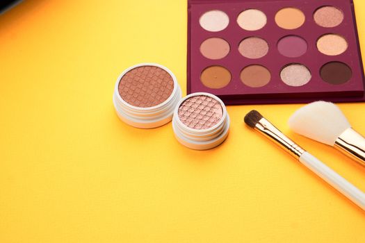 Professional eyeshadows and makeup brushes on a yellow background make-up decoration. High quality photo