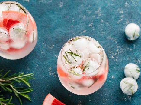 infused detox water or alcoholic or non-alcoholic cocktail with grapefruit and rosemary ice in glass on green cement background. healthy eating or holyday drink concept, copy space for text.