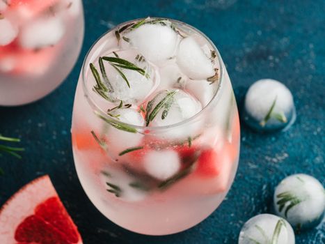 infused detox water or alcoholic or non-alcoholic cocktail with grapefruit and rosemary ice in glass on green cement background. healthy eating or holyday drink concept, copy space for text.