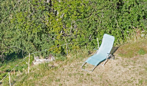 One empty folding garden chair for relaxing stands on the green grass