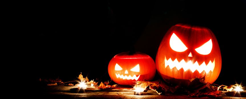 Halloween pumpkin head lanterns and burning candles on black background