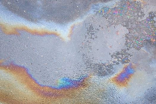 Spills and oil pollution on the road Leads to beautiful patterns and colors.Color gasoline fuel spot on black asphalt, industrial details concept.