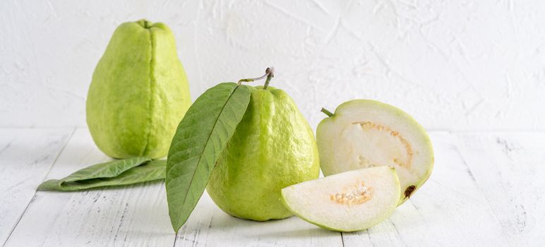 Delicious beautiful Guava set with fresh leaves isolated on bright white wooden table background, close up.