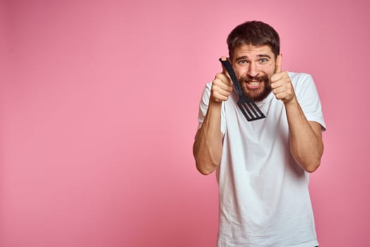 Man with spatula in hands kitchen accessories model emotions pink background cropped view Copy Space. High quality photo