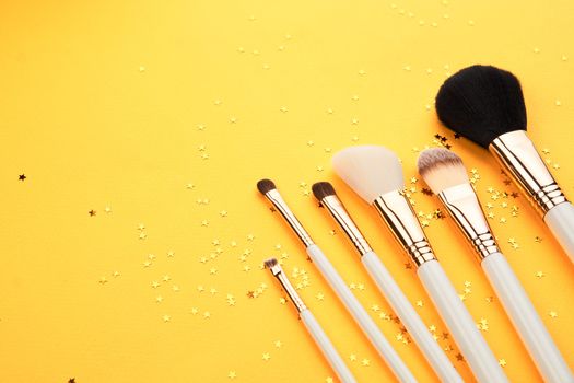 Makeup brushes in different sizes on a yellow background and glitter cropped look. High quality photo