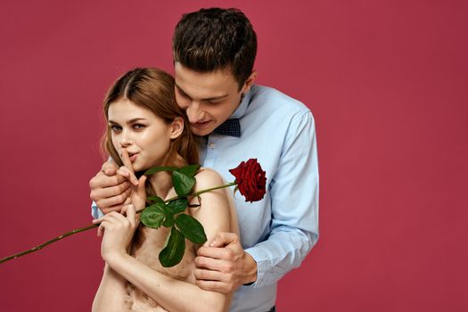 enamored man and woman with a red flower on a pink background hug each other Copy Space. High quality photo