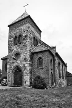 historic church with a bell tower in the village of Grochowo in Poland, black and white