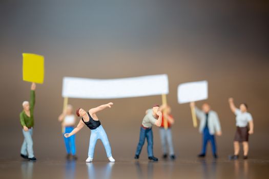 Miniature people , Crowd of protesters people raised hands and shouting on wooden background.