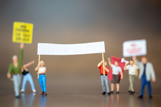 Miniature people , Crowd of protesters people raised hands and shouting on wooden background.