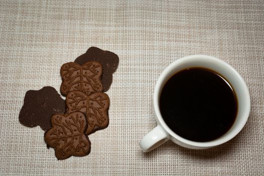 Coffee in a white cup and chocolate cookies, top view