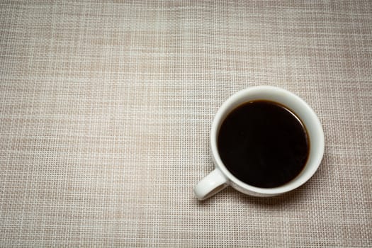 Coffee in a white cup on a light background, top view