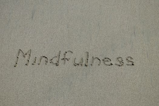 mindfulness concept, mindful living, text written on the sand of beach.