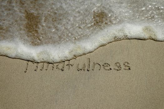 mindfulness concept, mindful living, text written on the sand of beach.