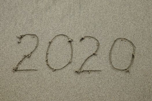 2020 drawn on the sand beach, new year concept. bye 2020 text is written by hand on the beach sand.