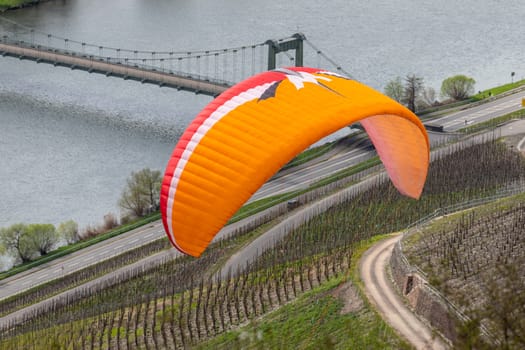 Flying paraglider over the valley of river Moselle and over vineyards