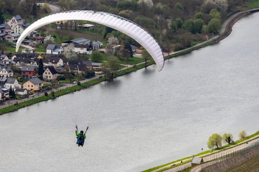 Flying paraglider over the valley of river Moselle and over vineyards