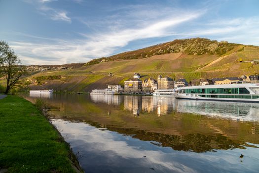 View at the city of Bernkastel-Kues at river Moselle with passenger ships and mountains with vineyards in the background