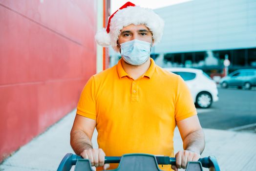 mature man with medical mask and christmas hat shopping.