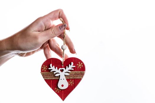 Hand holding heart shaped Christmas decoration isolated on white.