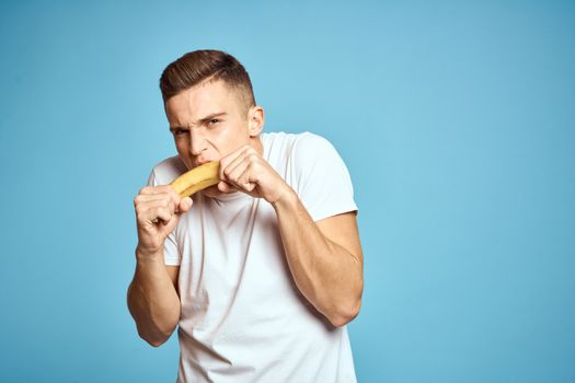 Happy man with fresh fruits gesturing with hands blue background white t-shirt vitamins bananas High quality photo