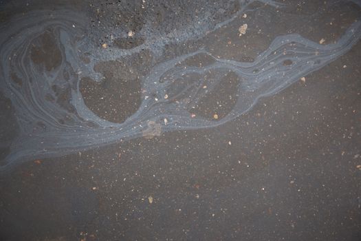 Abstract rainbow effect background, colorful gas stain on wet asphalt caused by a leak under a car or truck.Environmental pollution concept.