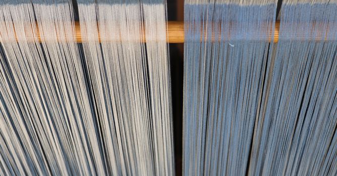Close up of a lot of threads in a weaving machine called a loom