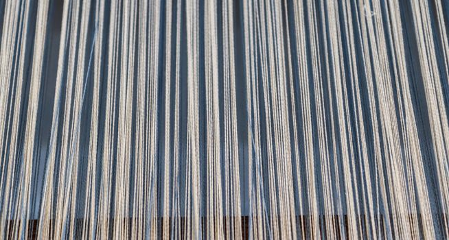 Close up of a lot of threads in a weaving machine called a loom