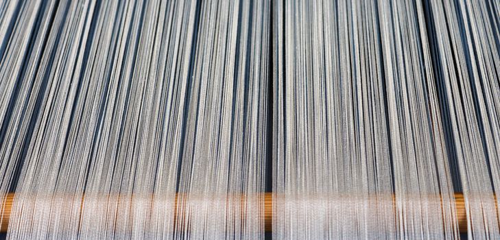 Close up of a lot of threads in a weaving machine called a loom