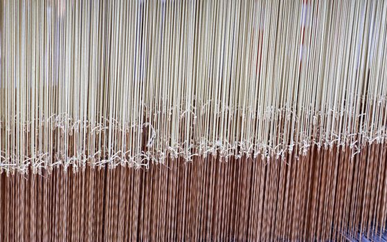 Close up of a lot of threads in a weaving machine called a loom