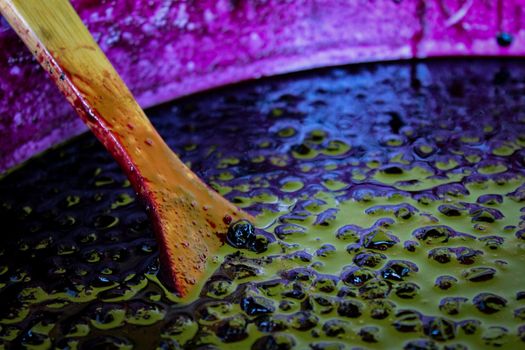 A wooden spoon in a pot where is chokeberry jam. The process of preparing chokeberry (aronia) jam. Zavidovici, Bosnia and Herzegovina.