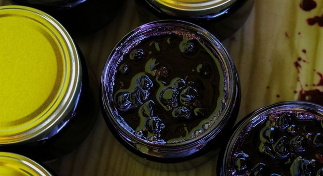 Banner. Homemade chokeberry jam. Full jars of homemade chokeberry jam on a tray. Aronia jam. Zavidovici, Bosnia and Herzegovina.