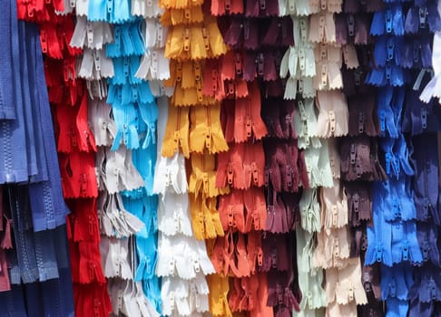 Detailed close up view on samples of zippers in different colors found at a fabrics market.