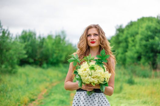 A beautiful young blonde girl collected a bouquet of wildflowers. Enjoy a walk on a warm summer day.