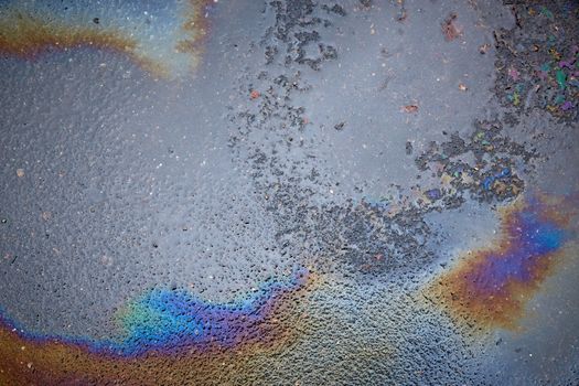 Abstract rainbow effect background, colorful gas stain on wet asphalt caused by a leak under a car or truck.Environmental pollution concept.