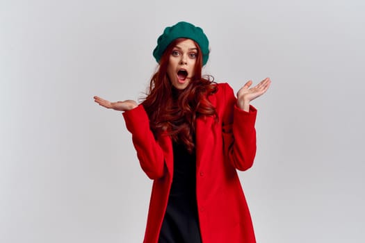 Portrait of a woman in a red coat and in a green hat dark clothes light background model cropped view. High quality photo