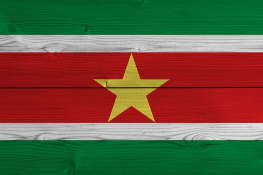 Suriname flag painted on old wood plank. Patriotic background. National flag of Suriname