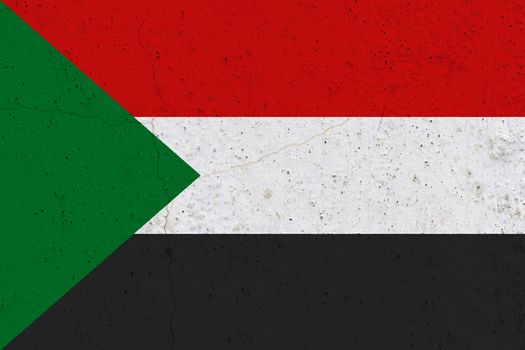 Sudan flag on concrete wall. Patriotic grunge background. National flag of Sudan