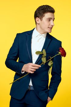 Gentleman in classic suit on yellow background with red rose romance cropped view. High quality photo