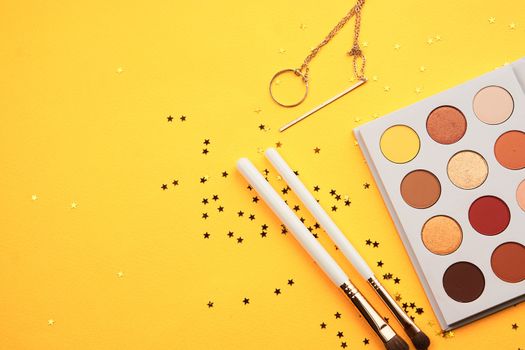 Eyeshadows and makeup brushes on a yellow background top view professional cosmetics. High quality photo