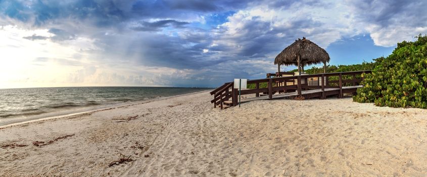 Tiki hut Boardwalk leads down to the white sand of Barefoot Beach in Bonita Springs, Florida