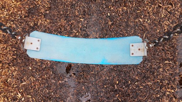 blue swing seat with water puddle on mulch or wood chips